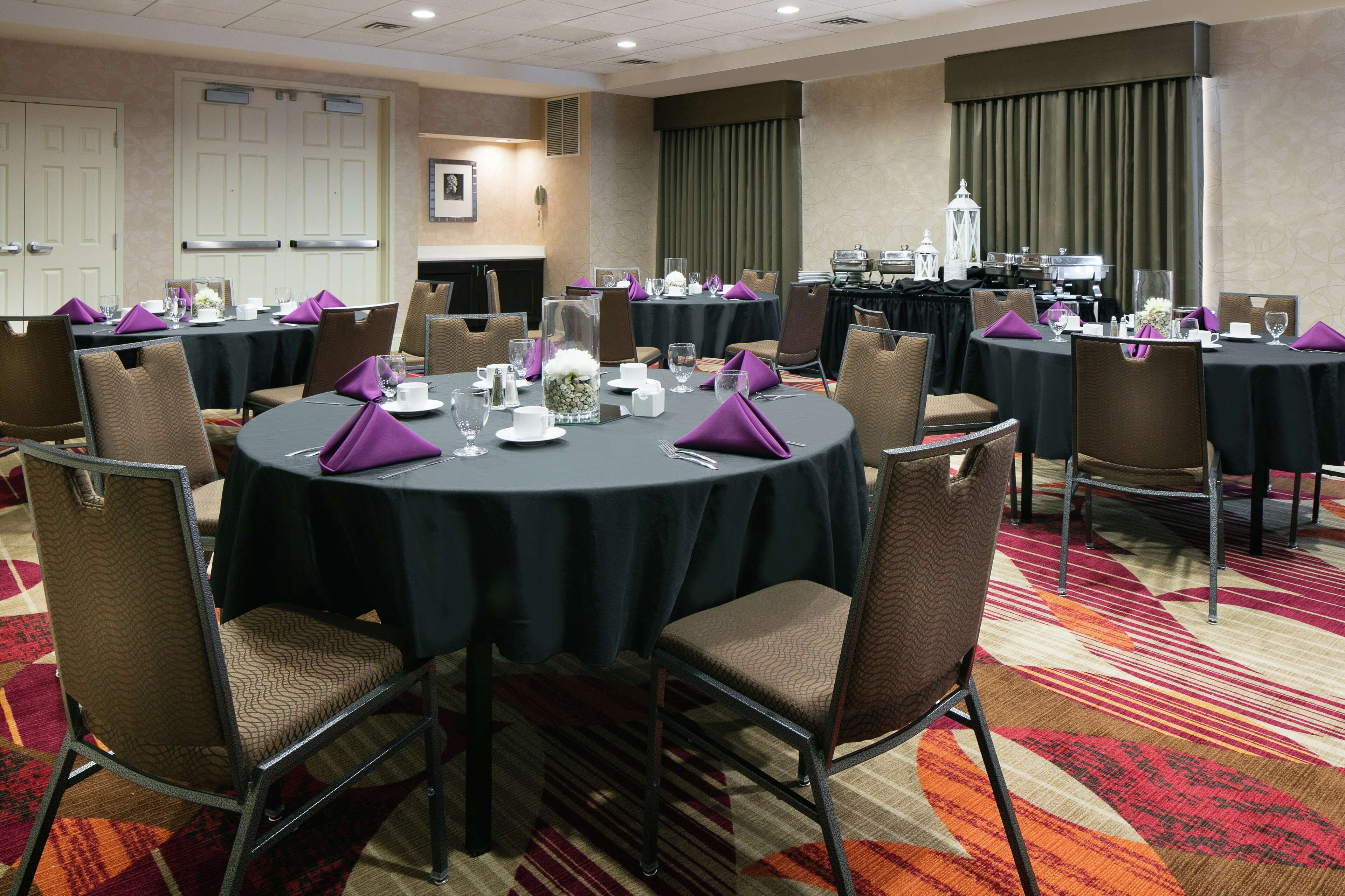 A conference room with round tables, chairs, and a carpeted floor.