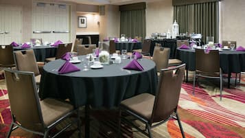 A conference room with round tables, chairs, and a carpeted floor.