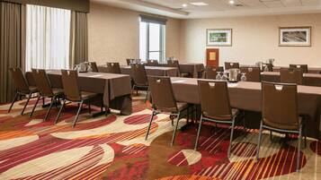 A conference room with multiple tables and chairs, arranged in a U-shape.