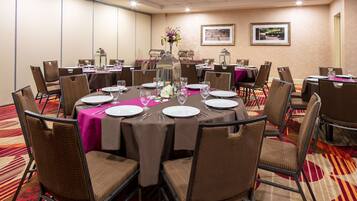 A conference room with round tables, brown chairs, and a carpeted floor.