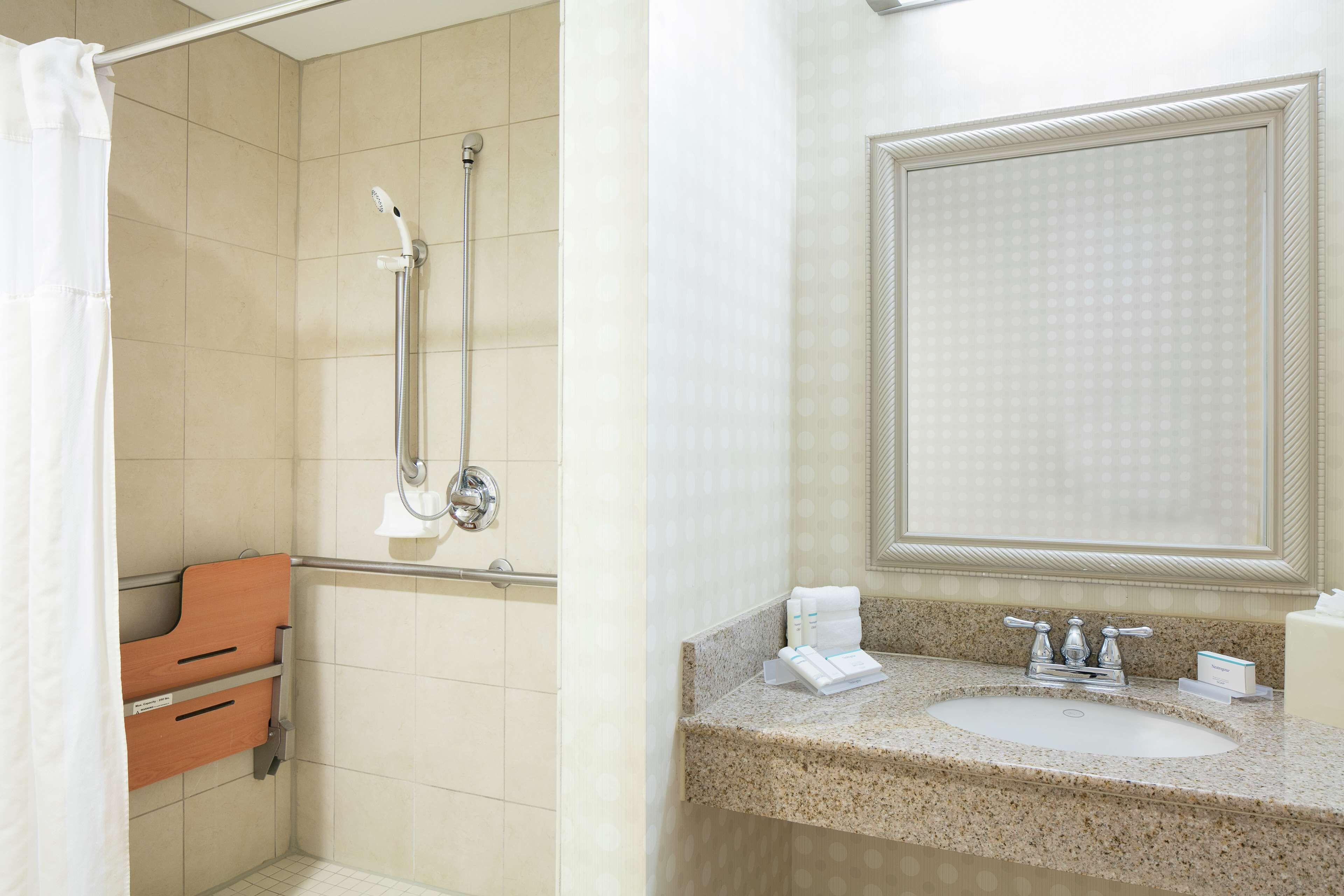 A bathroom with a shower, a vanity with a sink, and a mirror.
