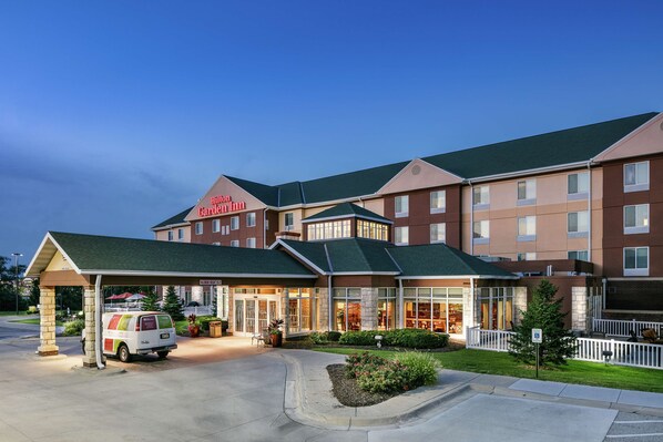 A hotel with a covered entrance, a van parked outside, and a well-maintained lawn. - Hilton Garden Inn Omaha West (Omaha)
