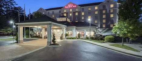 A Hilton Garden Inn with a well-lit entrance, a covered waiting area, and a visible parking lot.