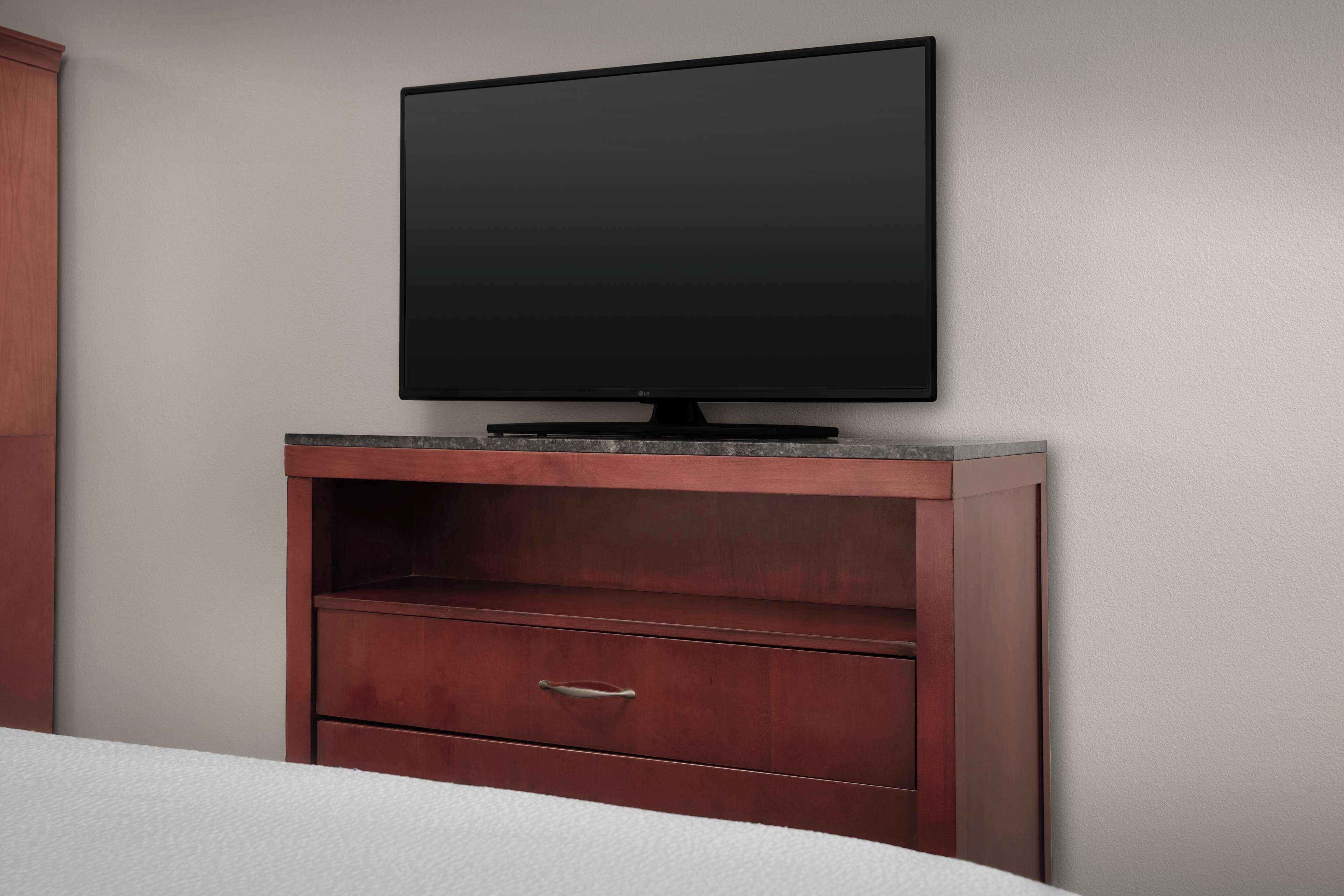 Televisor de pantalla plana fixat en un armari de fusta amb un calaix inferior.