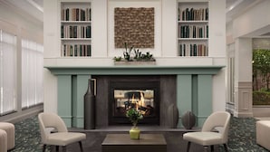 A room with a fireplace, bookshelves, two chairs, and a coffee table.