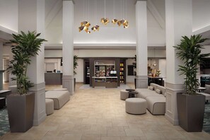 A spacious lobby with a central seating area, a shop, and large potted plants. - Hilton Garden Inn Columbia/Harbison (Columbia)