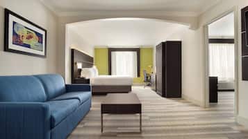 A hotel room with a blue sofa, a bed, a desk, and a large window with curtains.