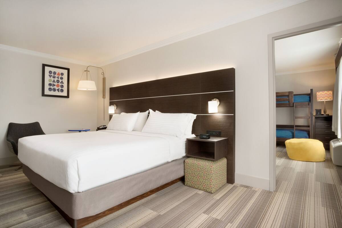 A modern hotel room with a large bed, bedside tables, a desk, and a chair.