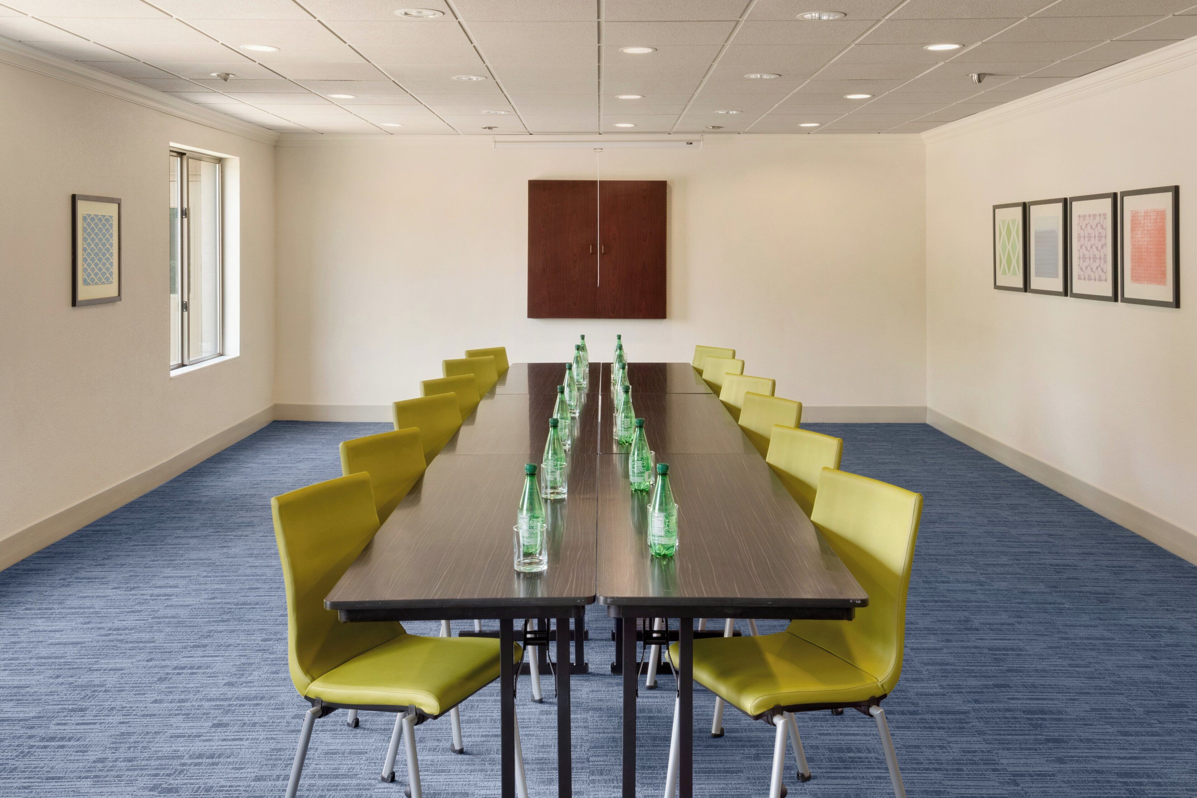 Un salón de conferencias con una mesa larga, sillas amarillas y cuadros en las paredes.