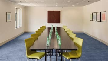 Un salón de conferencias con una mesa larga, sillas amarillas y cuadros en las paredes.