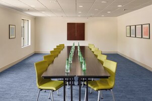 Un salón de conferencias con una mesa larga, sillas amarillas y cuadros en las paredes.