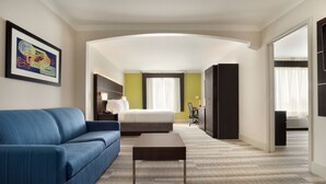 A hotel room with a blue sofa, a bed, a desk, and a large window. - Holiday Inn Express & Suites Dallas NE - Allen by IHG (Allen)