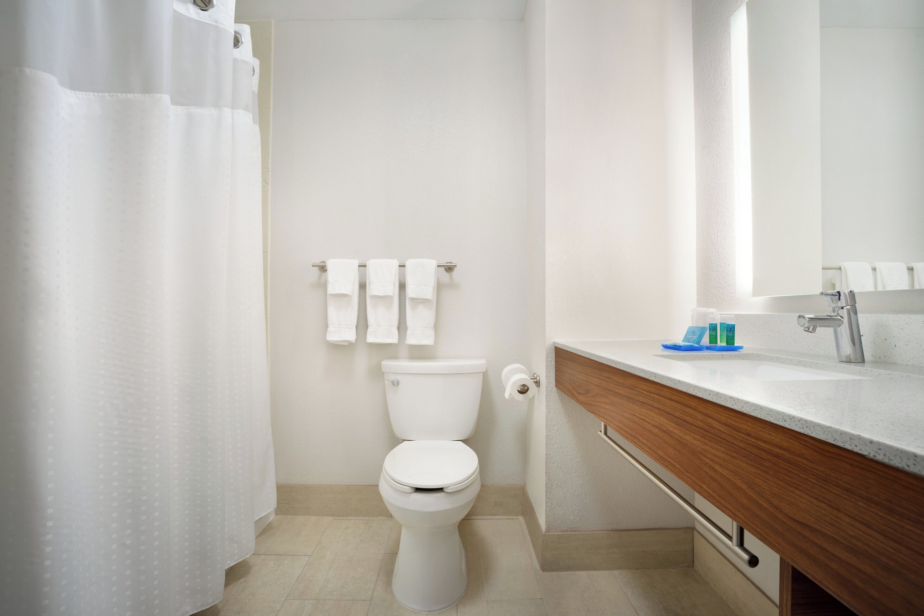 A modern bathroom with a toilet, a sink, and a shower curtain.