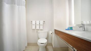 A modern bathroom with a toilet, a sink, and a shower curtain.