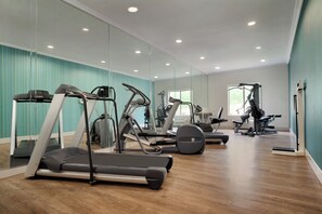 A gym with various exercise equipment, including treadmills and weight machines, with a large mirror wall and wooden flooring. - Holiday Inn Express & Suites Dallas NE - Allen by IHG (Allen)
