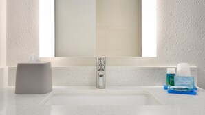 A bathroom sink with a tissue box, a soap dispenser, and a small blue item on the counter. - Holiday Inn Express & Suites Dallas NE - Allen by IHG (Allen)
