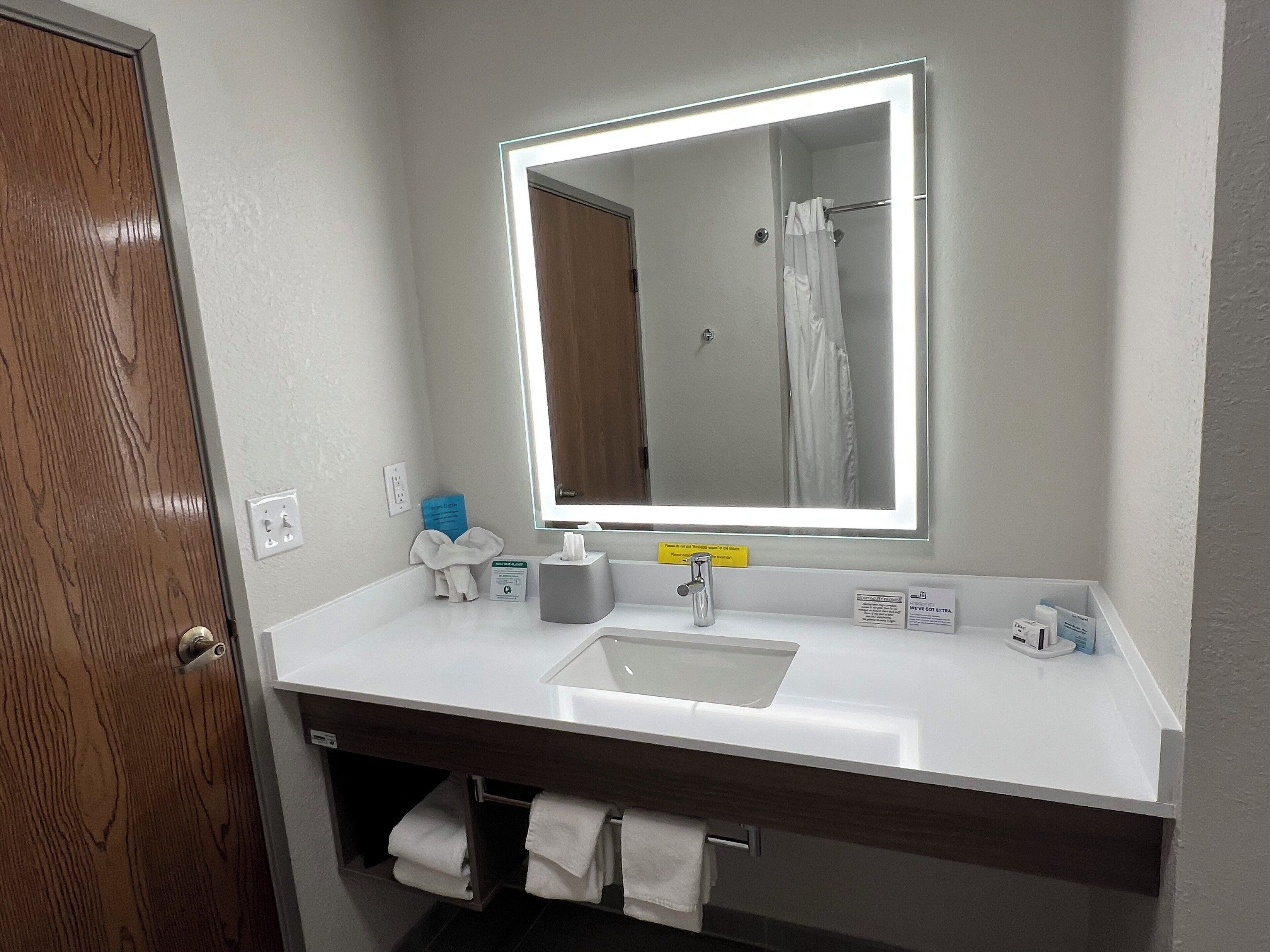 A modern bathroom with a white sink, a large mirror, and a towel rack.