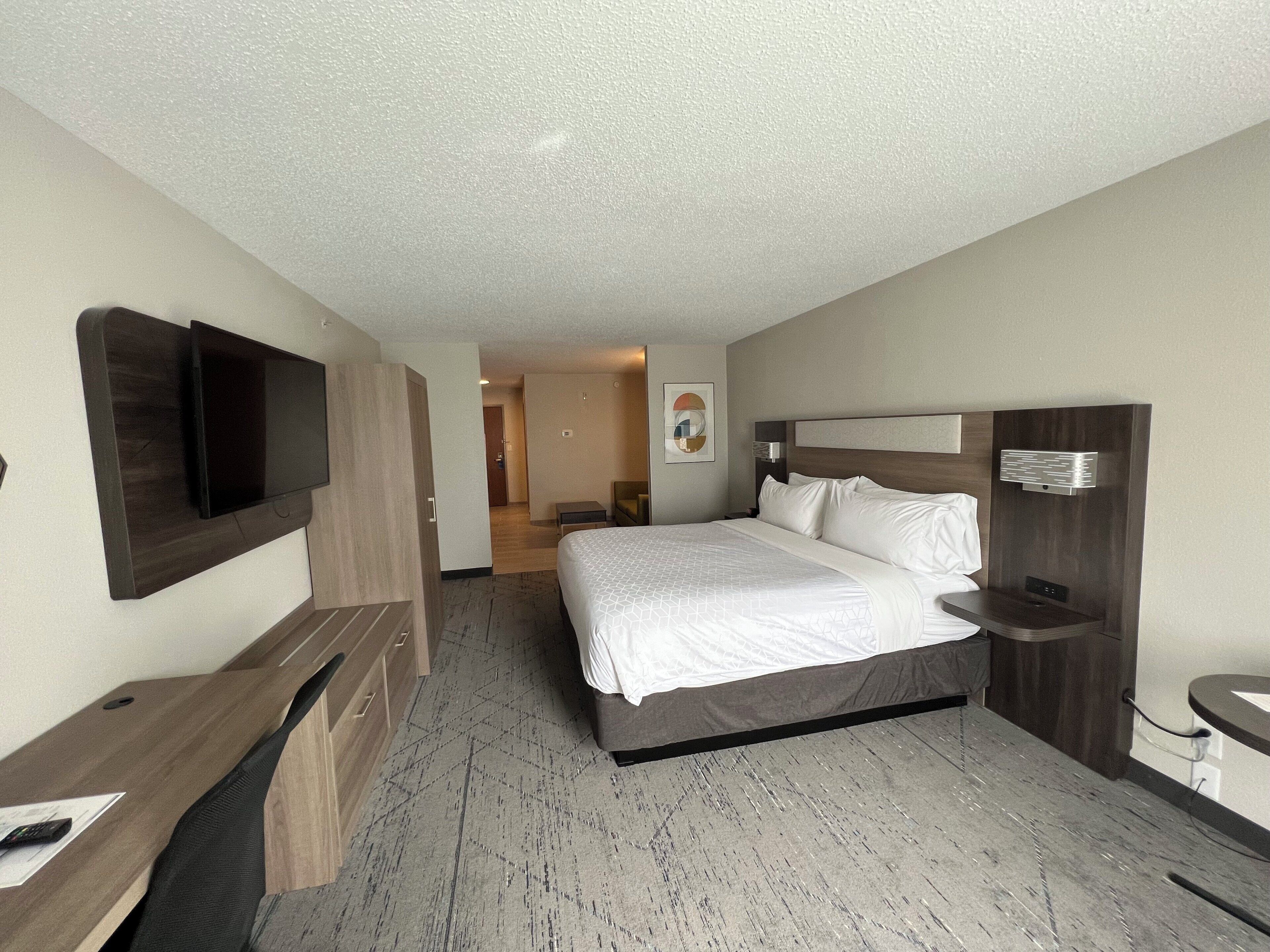 A hotel room with a bed, a desk, a TV, and a bathroom.