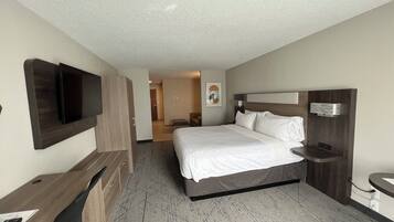 A hotel room with a bed, a desk, a TV, and a bathroom.