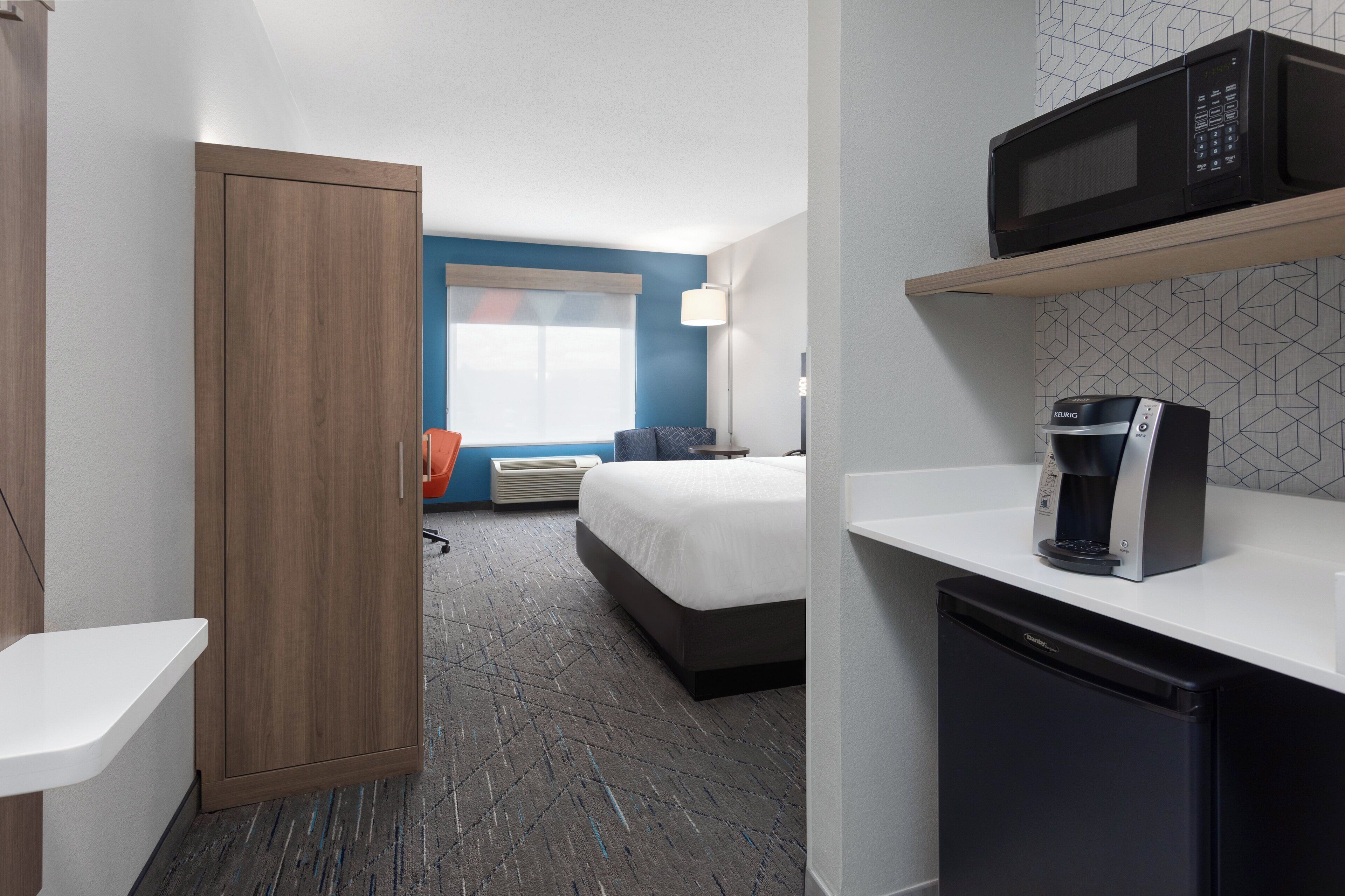 Une chambre d’hôtel équipée d’un lit, d’un four à micro-ondes, d’une machine à café, d’une armoire et d’un petit réfrigérateur.