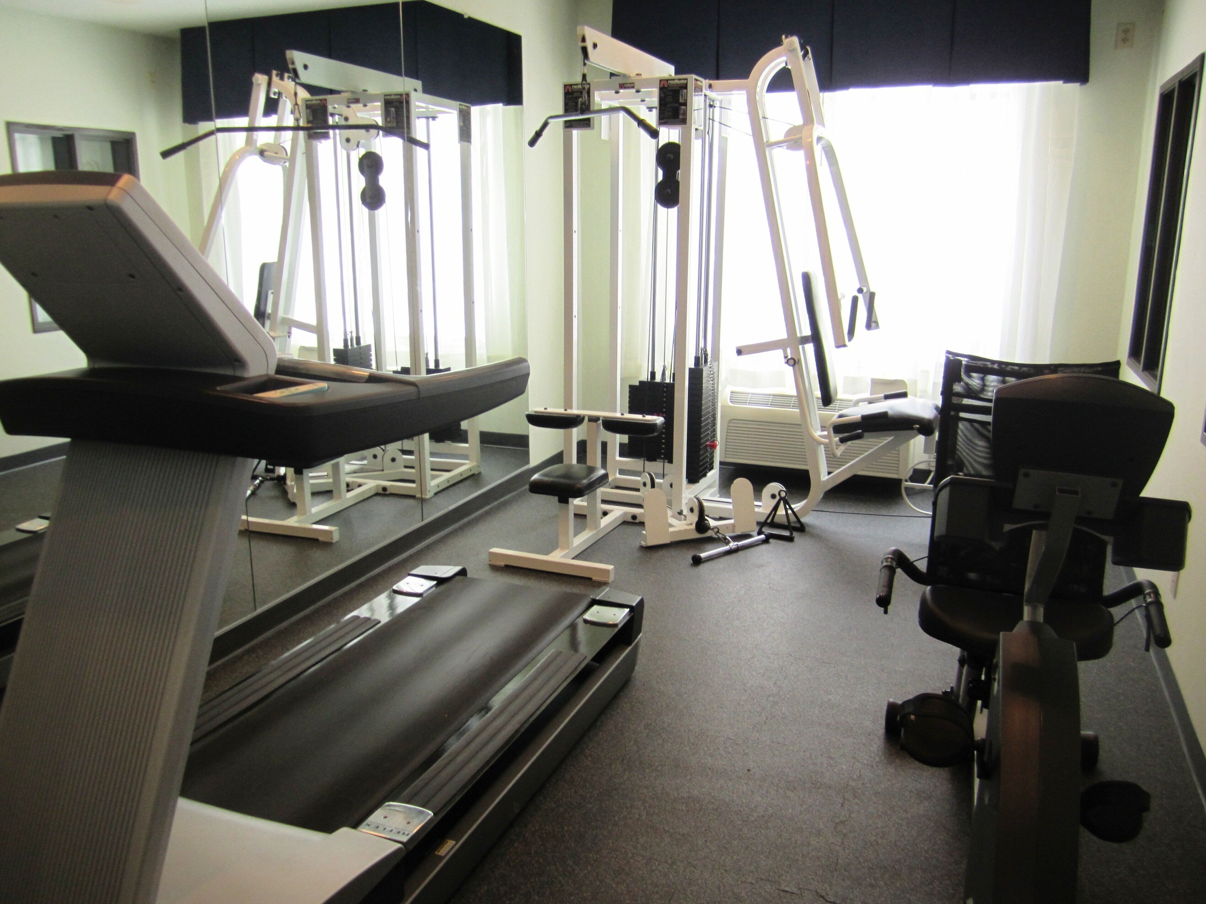 A gym with exercise equipment including a treadmill, weight machines, and a bench.