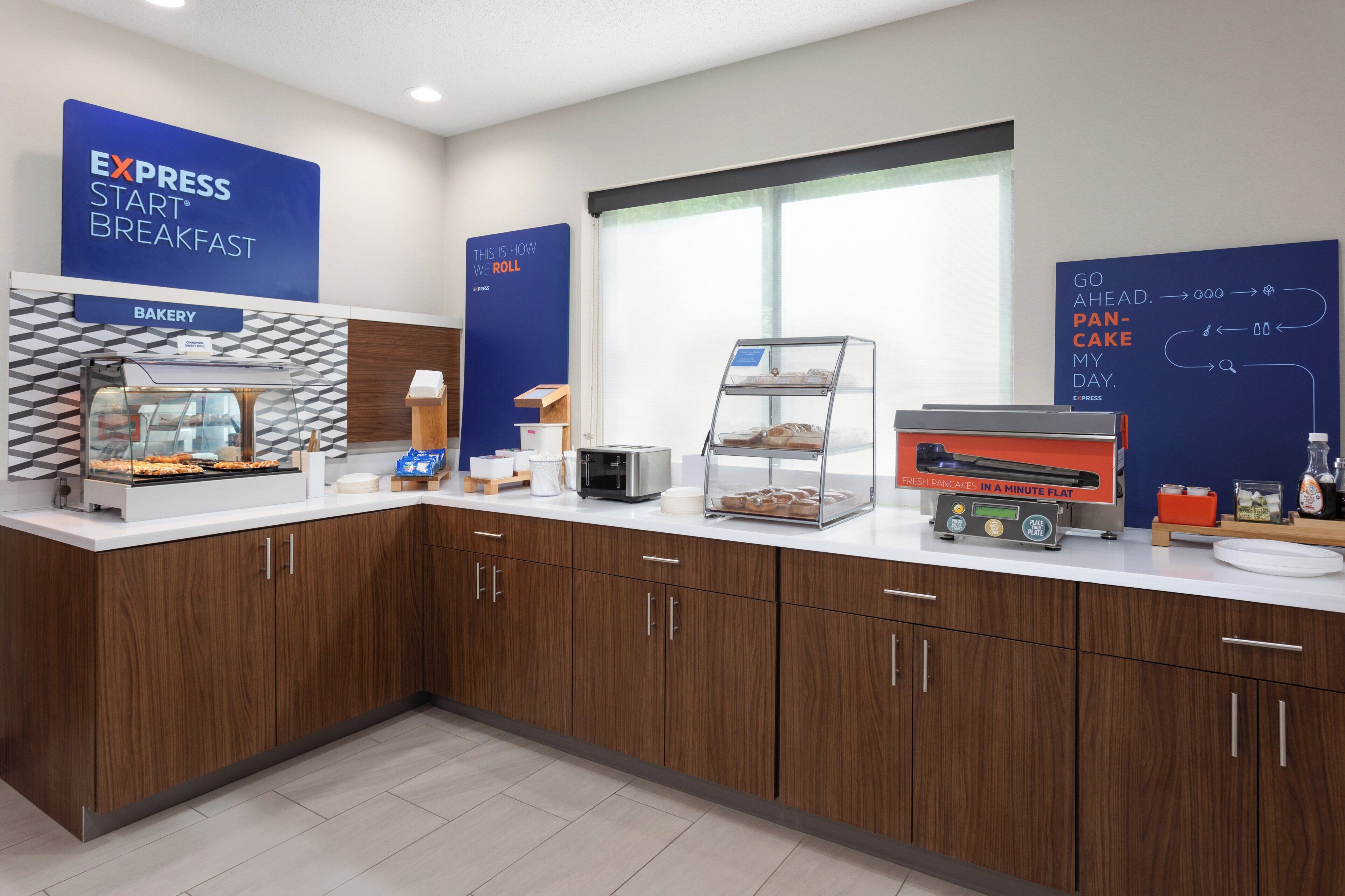 A breakfast area with a bakery display, a toaster, and a sign explaining the breakfast process.