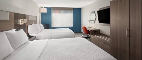 Een hotelkamer met twee bedden, een bureau met stoel, een televisie en een kledingkast.