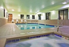Una piscina con plataforma de cerámica, barandillas de seguridad y zona de vestuarios.
