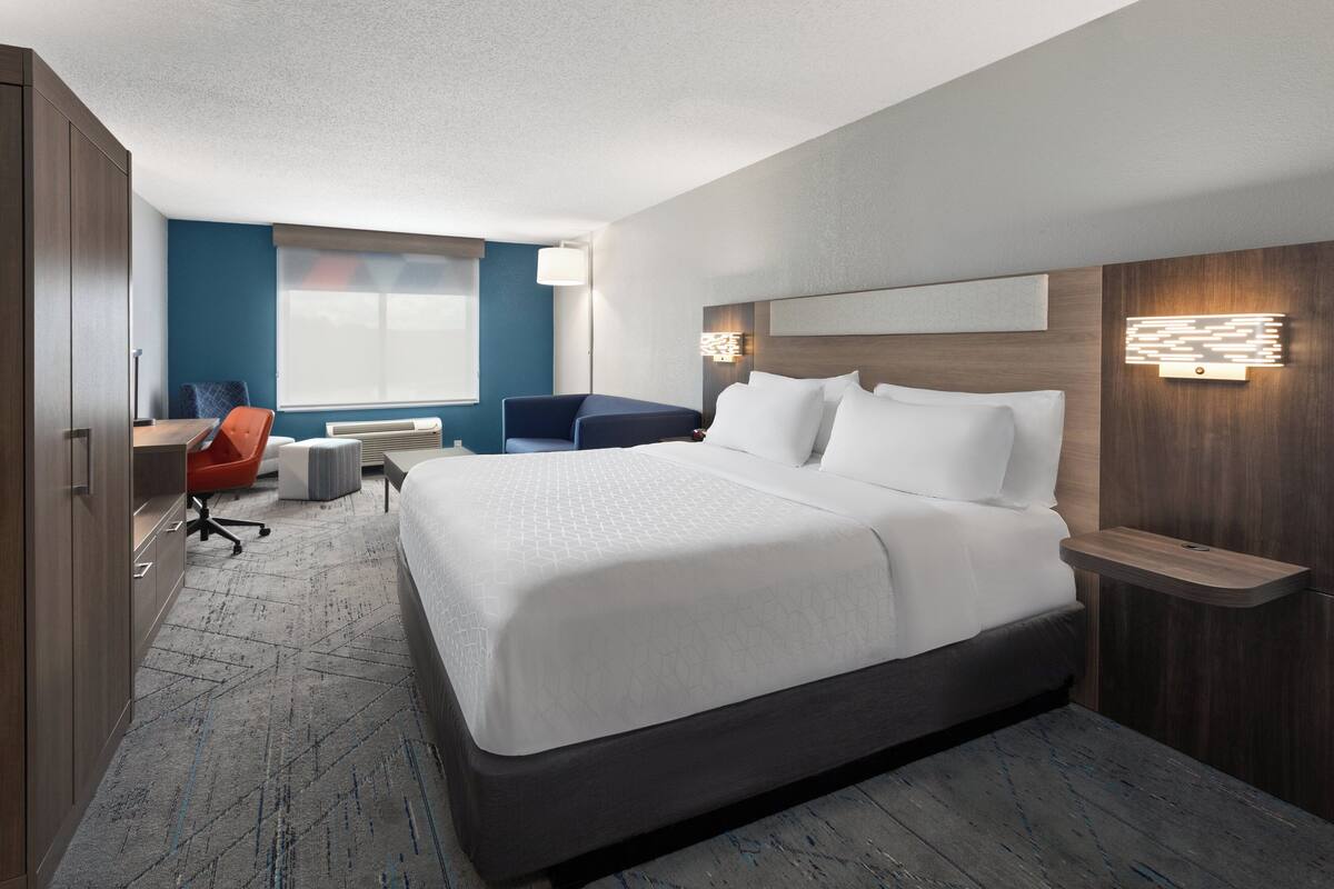Une chambre d’hôtel moderne avec un grand lit, un bureau, une chaise et une petite table.