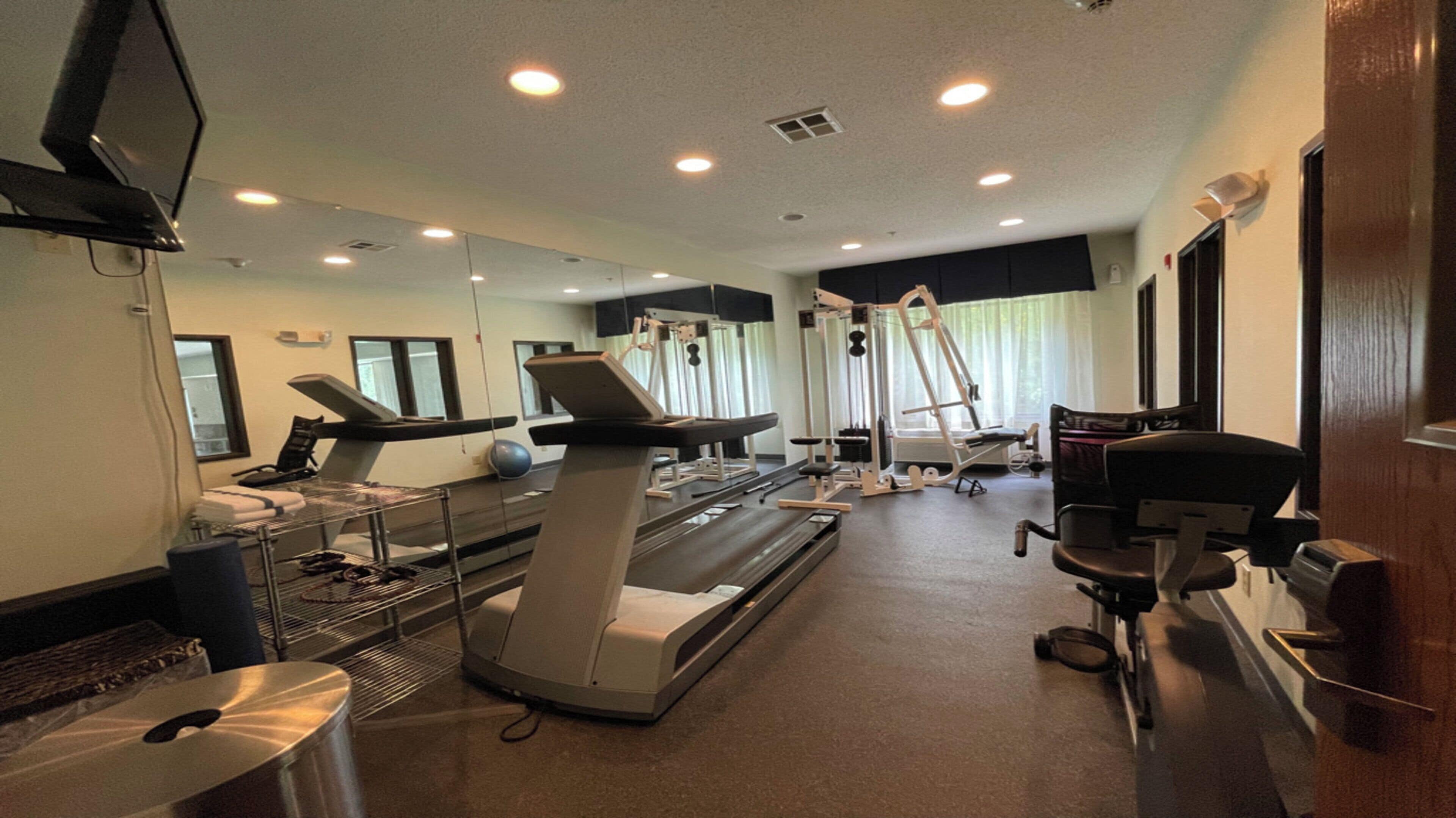 A fitness center with treadmills, exercise balls, and a mirrored wall.