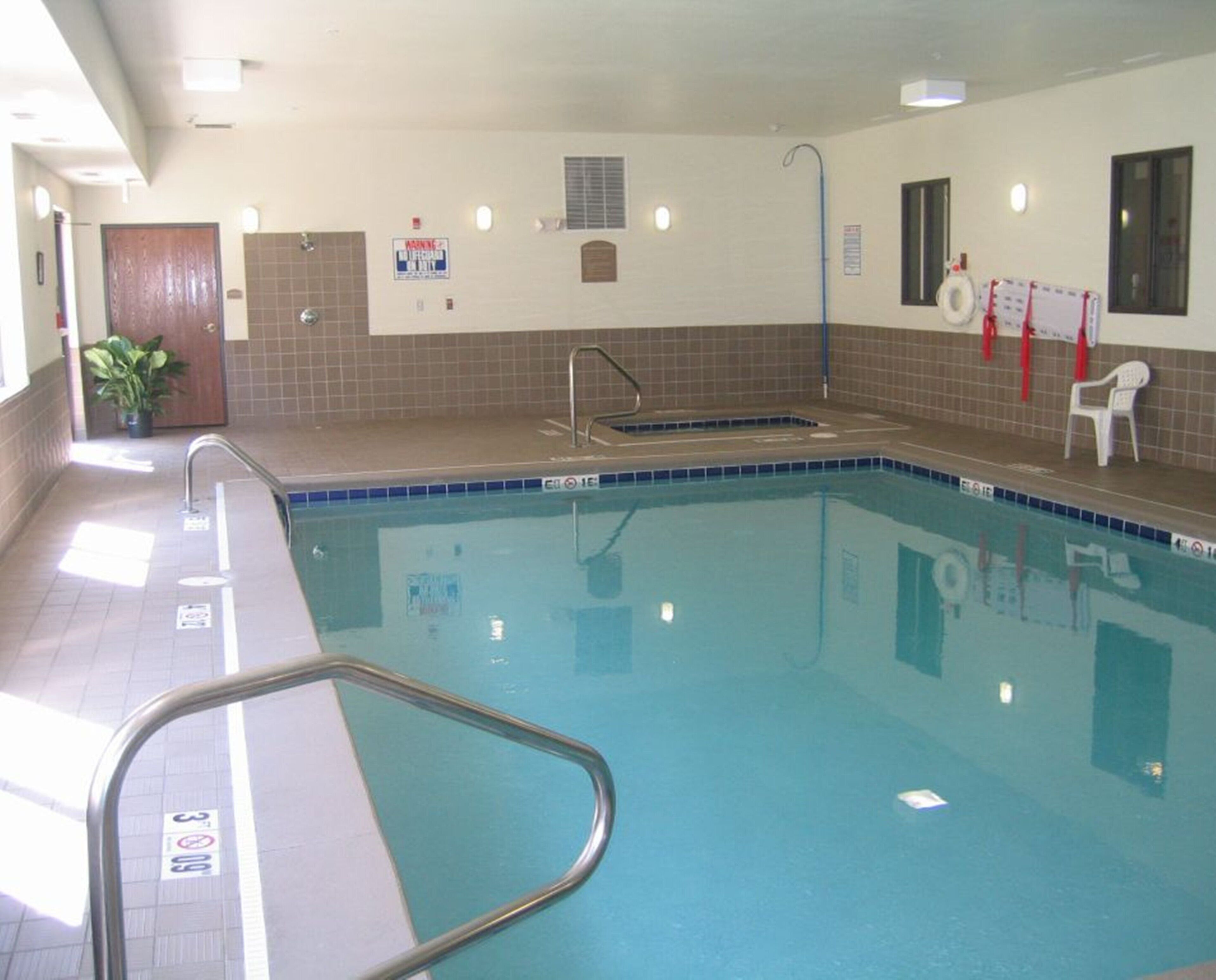 A swimming pool with a tiled deck, a lifeguard chair, and a sign indicating no lifeguard on duty.