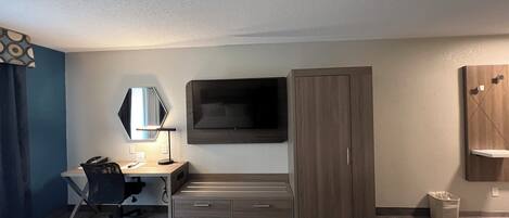 A hotel room with two beds, a desk with a chair, a television mounted on the wall, and a wardrobe.
