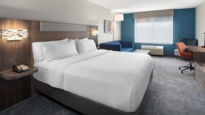 Ein Hotelzimmer mit einem großen Bett, einem Schreibtisch, einem Stuhl und einer kleinen Sitzecke.