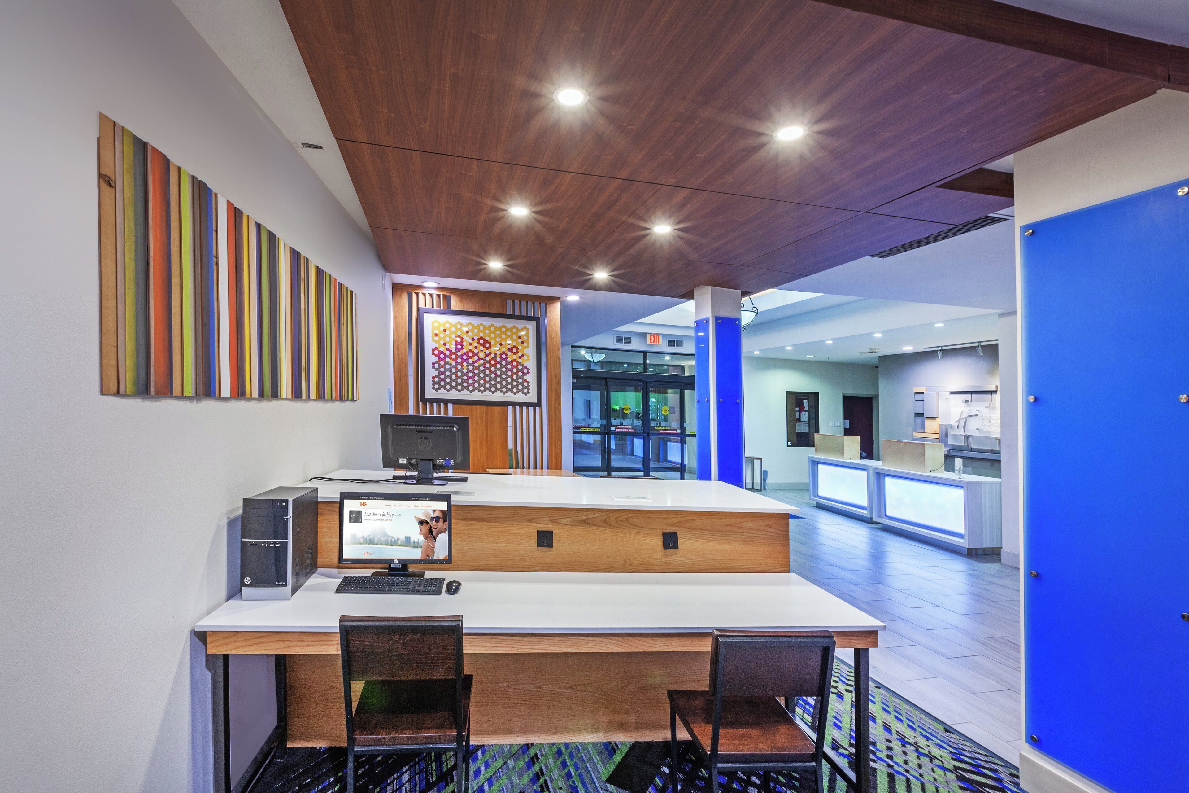 A reception area with a desk, chairs, a computer, and a colorful artwork on the wall.