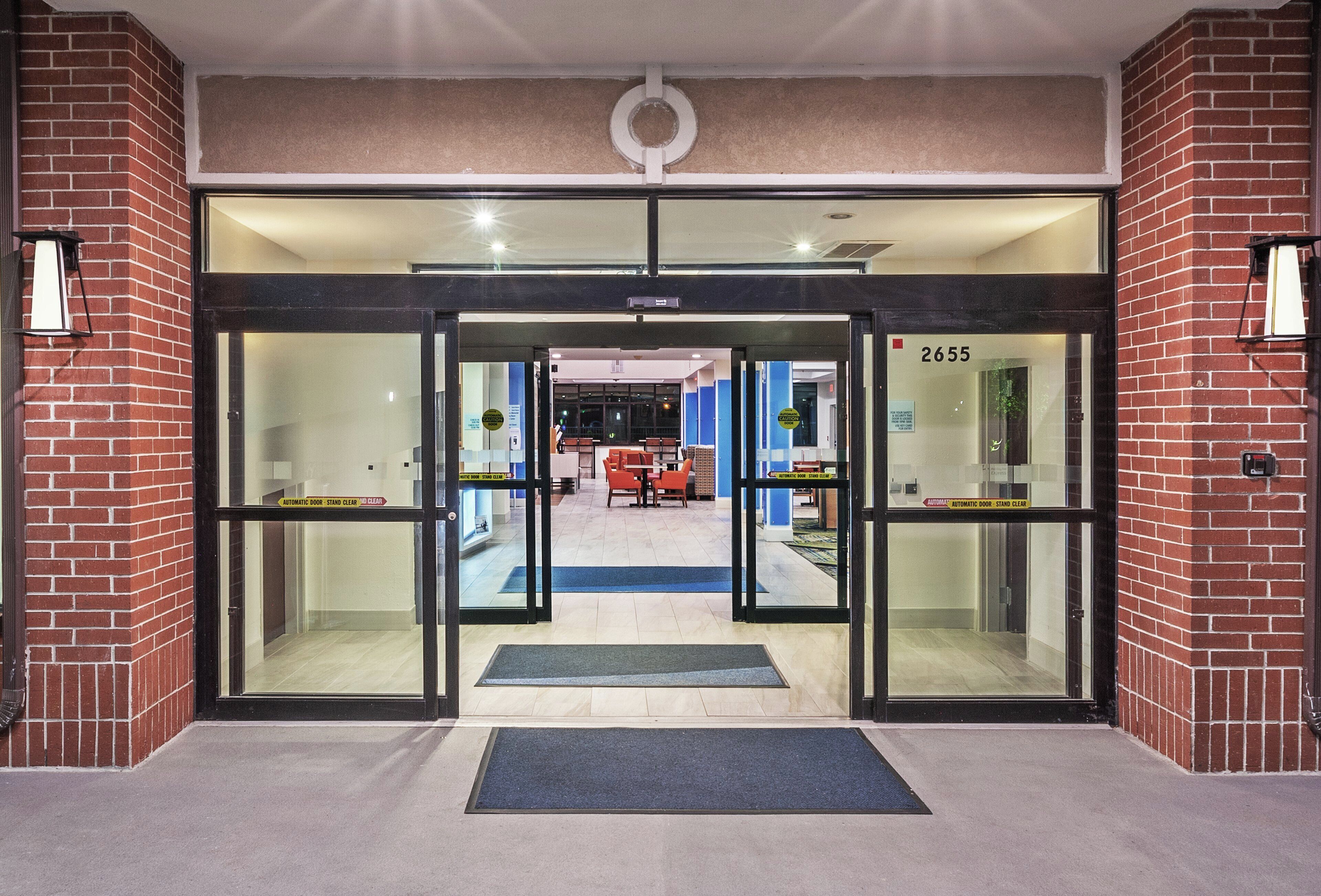 A hotel entrance with automatic doors, a blue mat, and a number 2655 sign.
