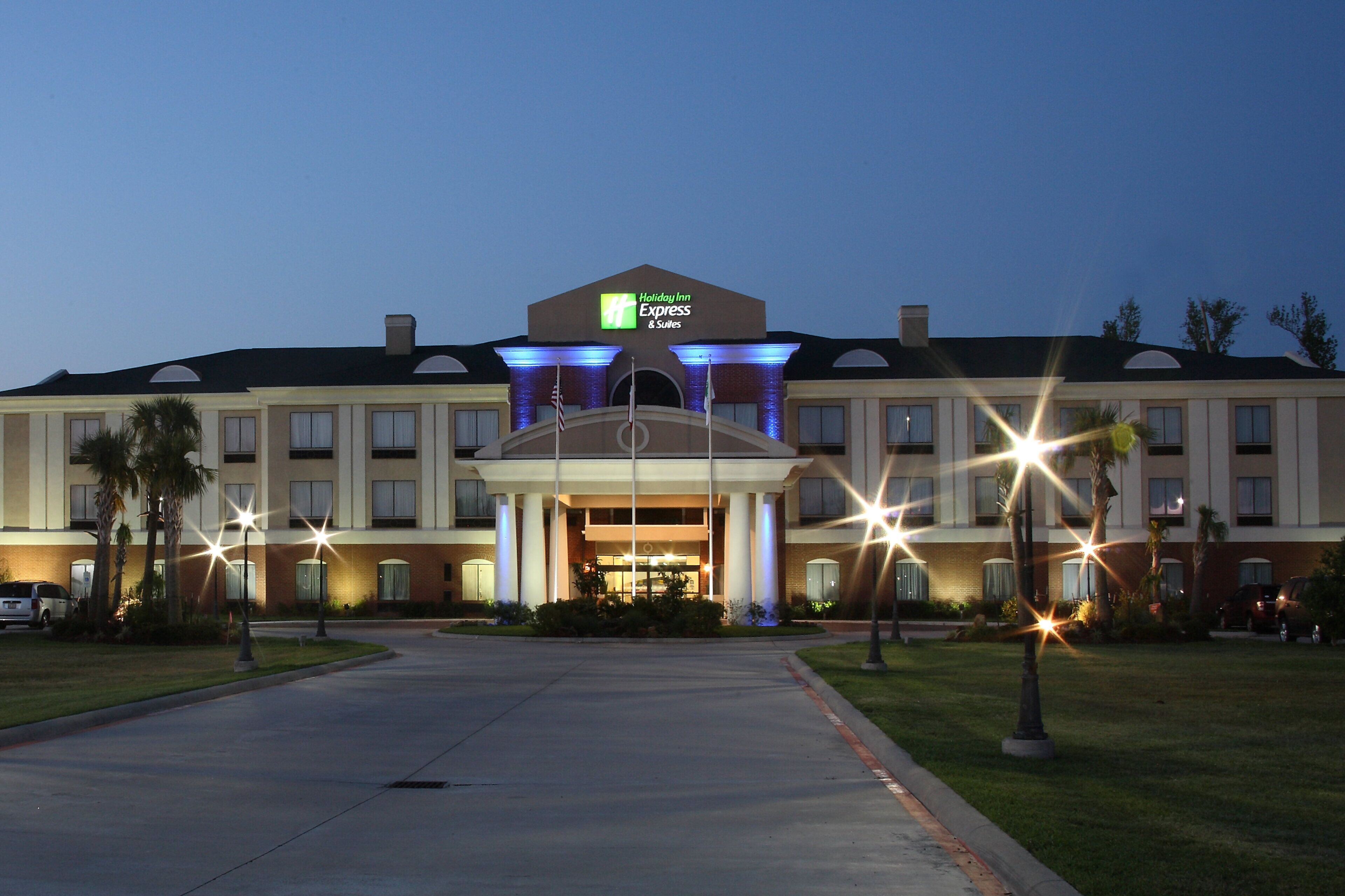 Un hotel Holiday Inn Express & Suites con entrada principal, varios pisos y un estacionamiento.