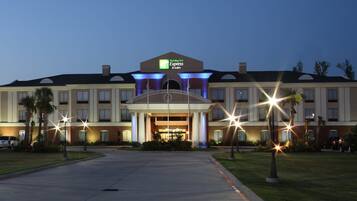 Un hotel Holiday Inn Express & Suites con entrada principal, varios pisos y un estacionamiento.
