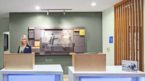 Zona de recepción con diseño moderno, incluyendo un gran letrero de Holiday Inn Express & Suites y un panel de madera a la derecha.