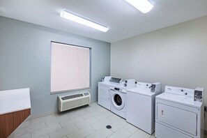 Une buanderie équipée d’un lave-linge, d’un sèche-linge et d’une bouche d’aération.