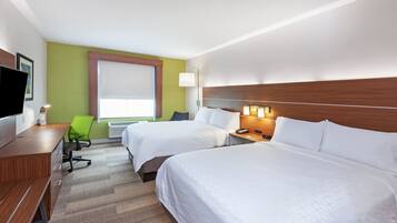 A hotel room with two beds, a desk, a chair, a TV, and a window with blinds.