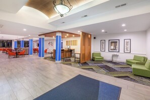 Un hall d’entrée spacieux au design moderne, comprenant un comptoir d’accueil, des espaces de détente et une moquette à motifs.