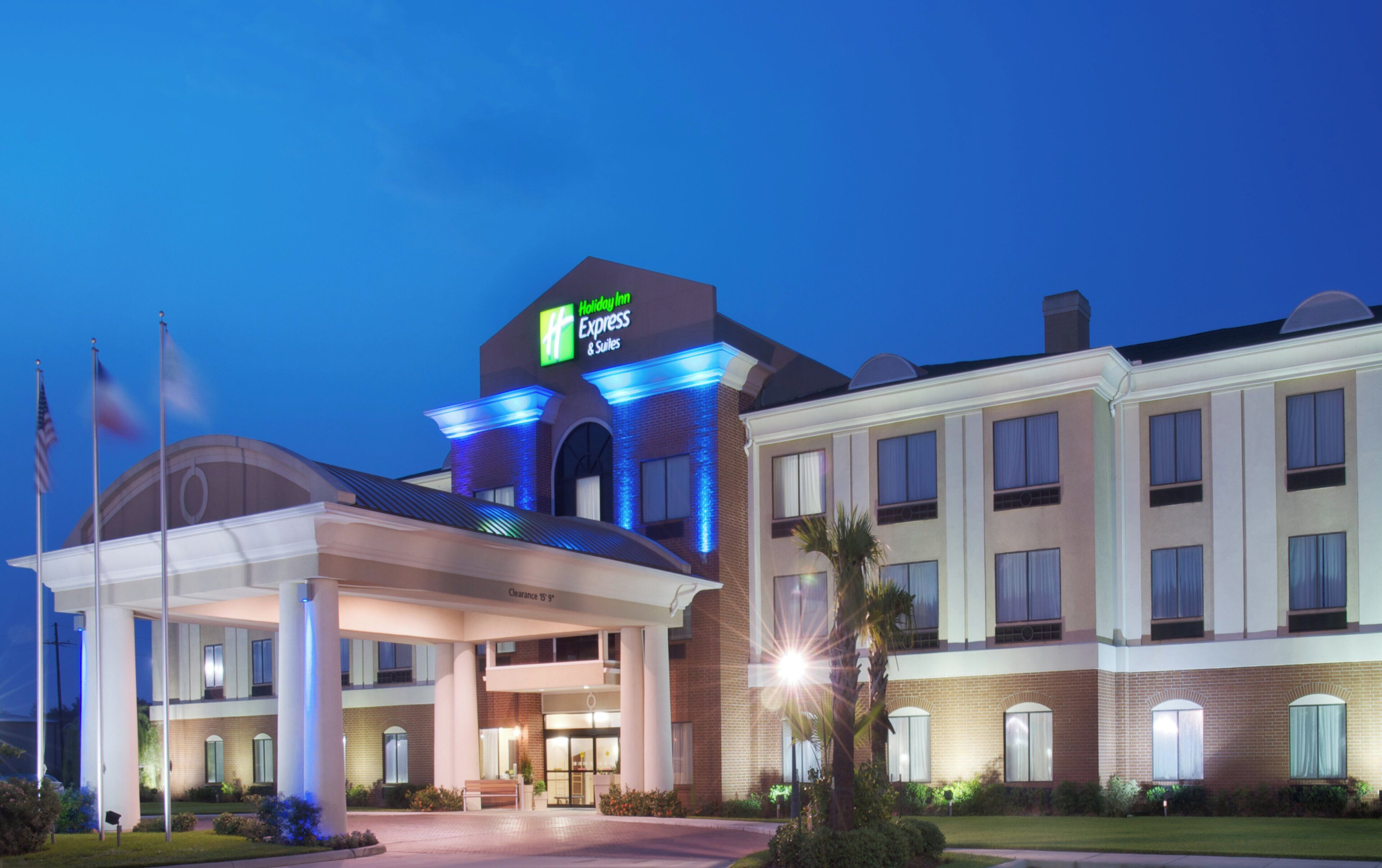 Un hotel Holiday Inn Express con entrada despejada, zona de estacionamiento techada y fachada bien iluminada.