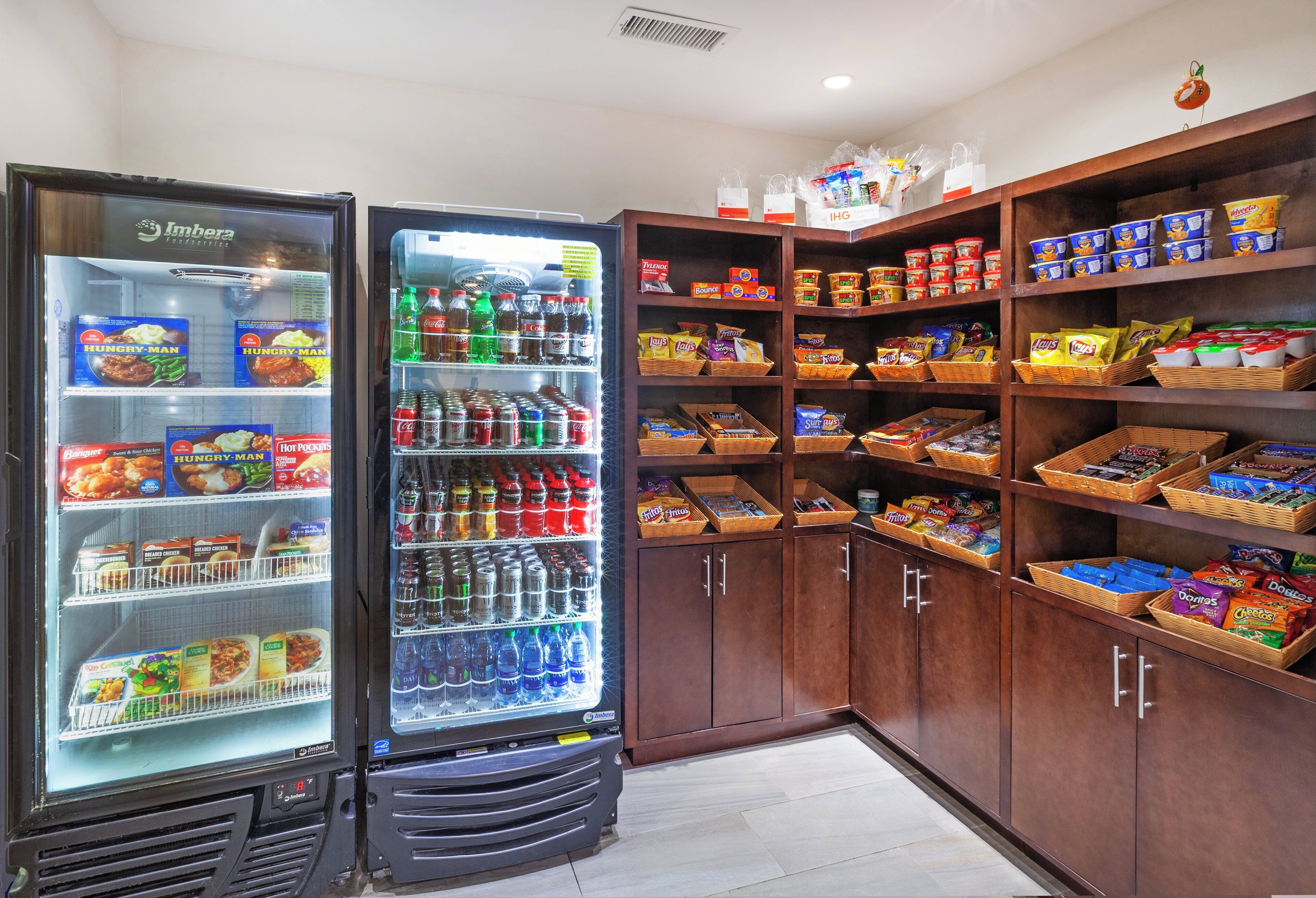 A food service area with a refrigerated display case and shelves stocked with snacks and beverages.