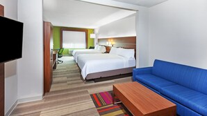 A hotel room with a large bed, a blue sofa, a wooden coffee table, and a flat-screen TV. - Holiday Inn Express Hotel & Suites Orange by IHG (Orange)