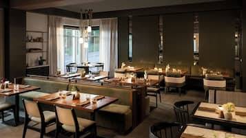 A restaurant with multiple dining areas, including booths and tables, with candles and table settings.