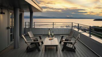 A deck with outdoor seating and a view of a marina.