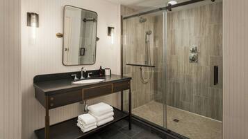 A modern bathroom with a glass-enclosed shower, a vanity with a sink, and a mirror.