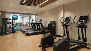 Un gimnasio con cintas de correr, elípticas y pelotas de ejercicio.