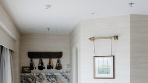 A modern kitchen with marble backsplash, wooden cabinets, and a dining area with two orange chairs and a white table. - The Harborvale, Autograph Collection (Burlington)