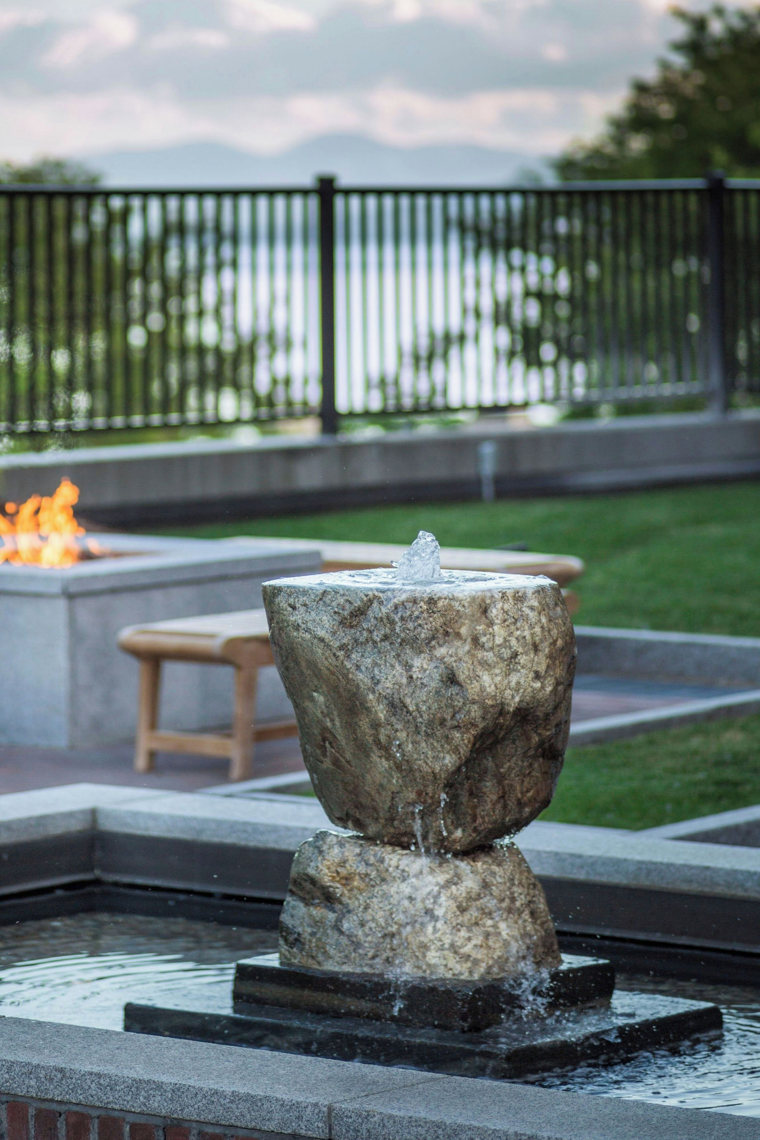 A stone fountain with water spouting from the top, surrounded by a pool.